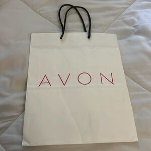 Avon white paper bag with black strings handles